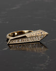 Contemporary gold ring with sharp silhouette and pavé diamonds, handmade by Bena Jewelry in Montreal, photographed against a deep-toned surface.