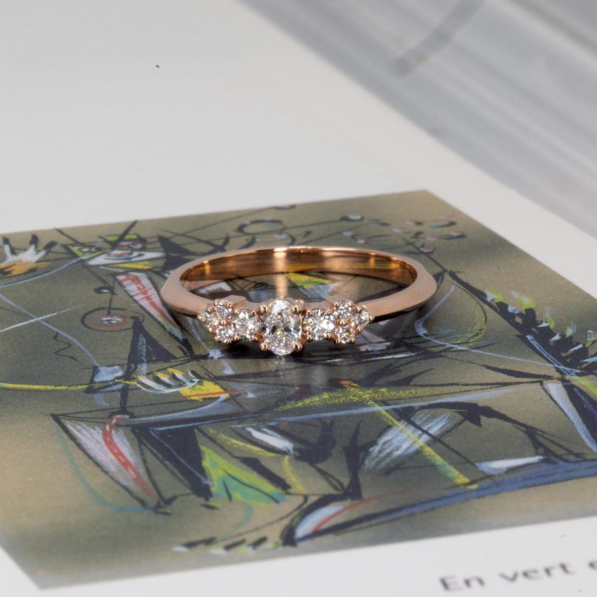 The Lile ring photographed against a muted beige surface, featuring a graceful mix of oval and round lab-grown diamonds in rose gold – crafted in Montreal by Bena Jewelry.