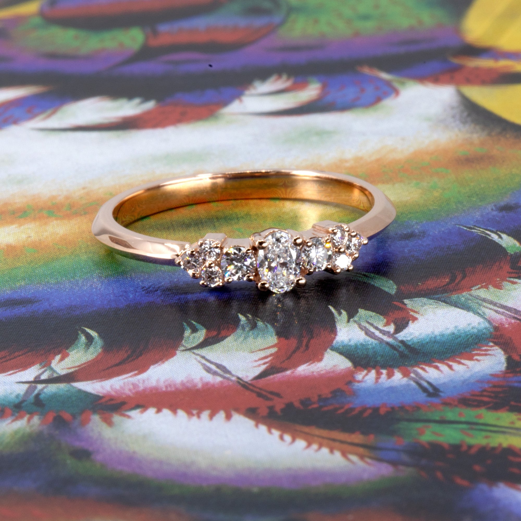 Elegant five-stone engagement ring in 14k rose gold with oval and round lab diamonds, styled by Bena Jewelry on a warm-toned backdrop – Canadian fine jewelry.