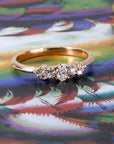 Elegant five-stone engagement ring in 14k rose gold with oval and round lab diamonds, styled by Bena Jewelry on a warm-toned backdrop – Canadian fine jewelry.