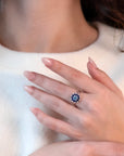Model wearing the Soleil Ring by Bena Jewelry, bold white gold ring with blue diamond centerpiece and sapphire halo.