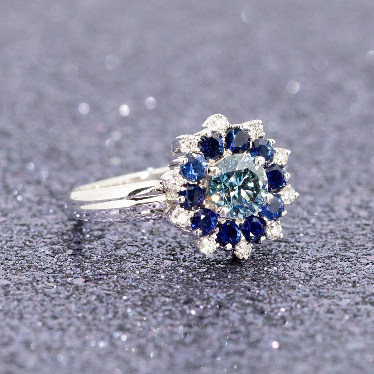 Soleil Ring on sparkly background, custom-made white gold design with lab-grown blue diamond and diamond accents.
