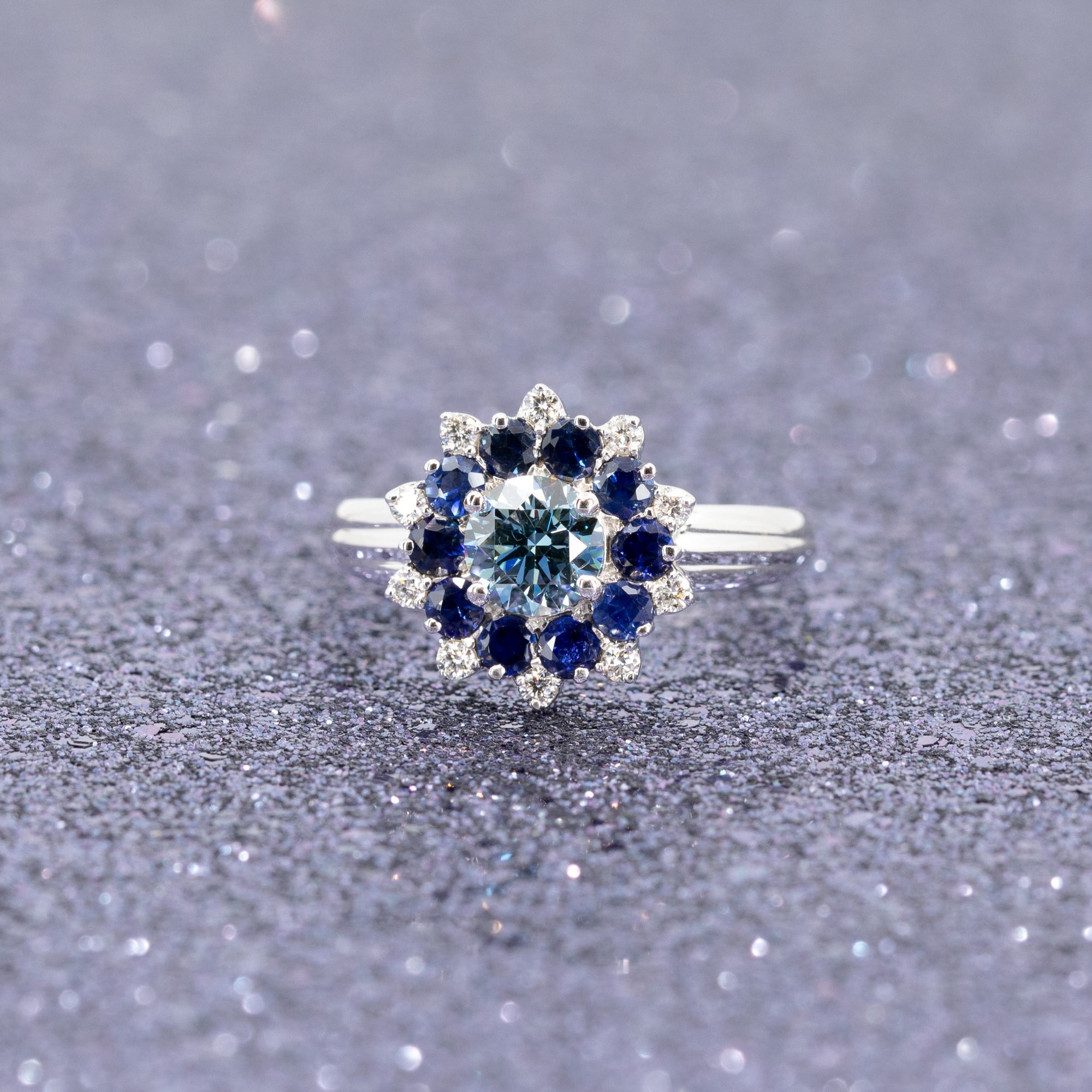 Elegant display of Soleil Ring by Bena Jewelry, bold white gold creation with sapphire and blue diamond details.