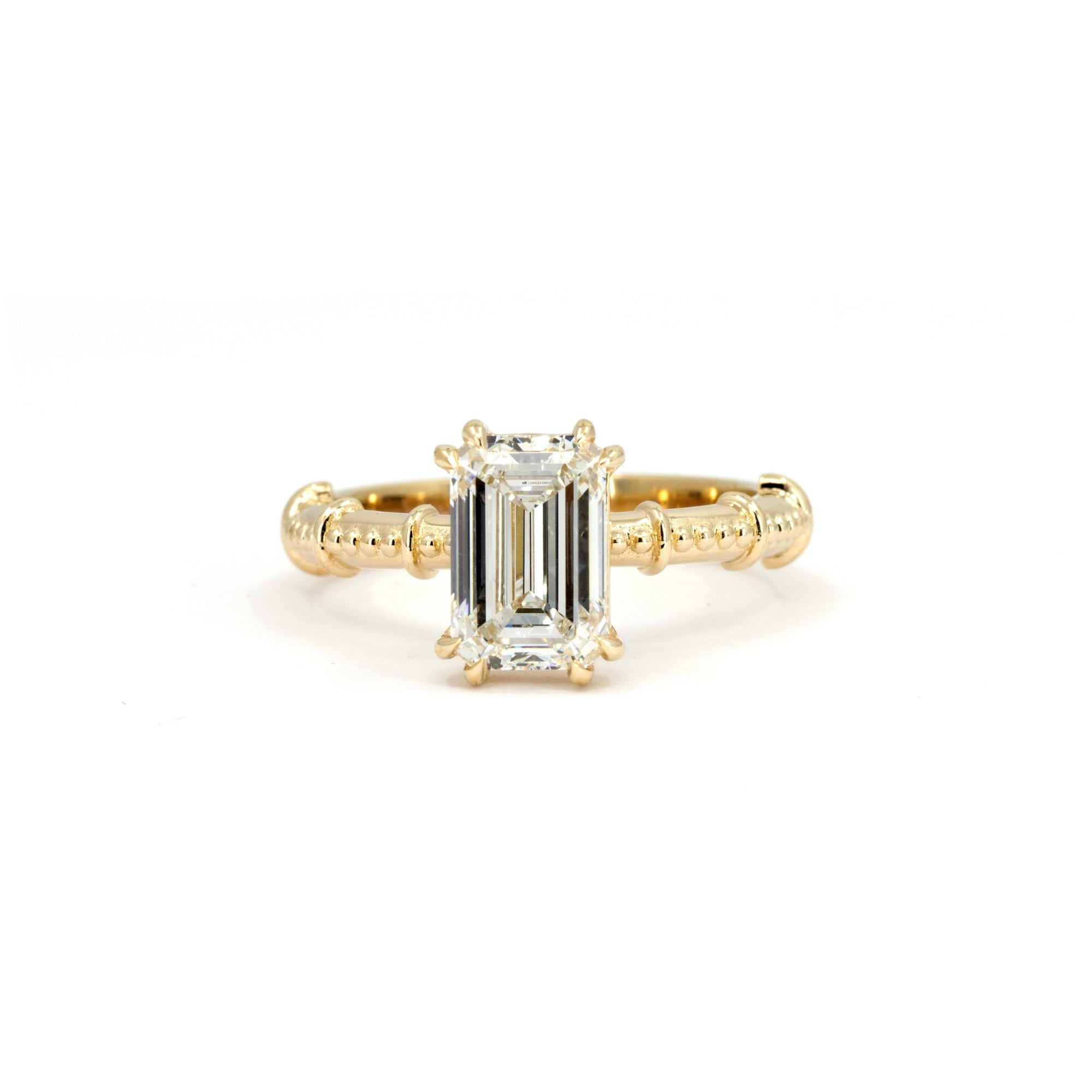 Emerald-cut diamond engagement ring in yellow gold with a milgrain band, handmade by Bena Jewelry in Montreal.