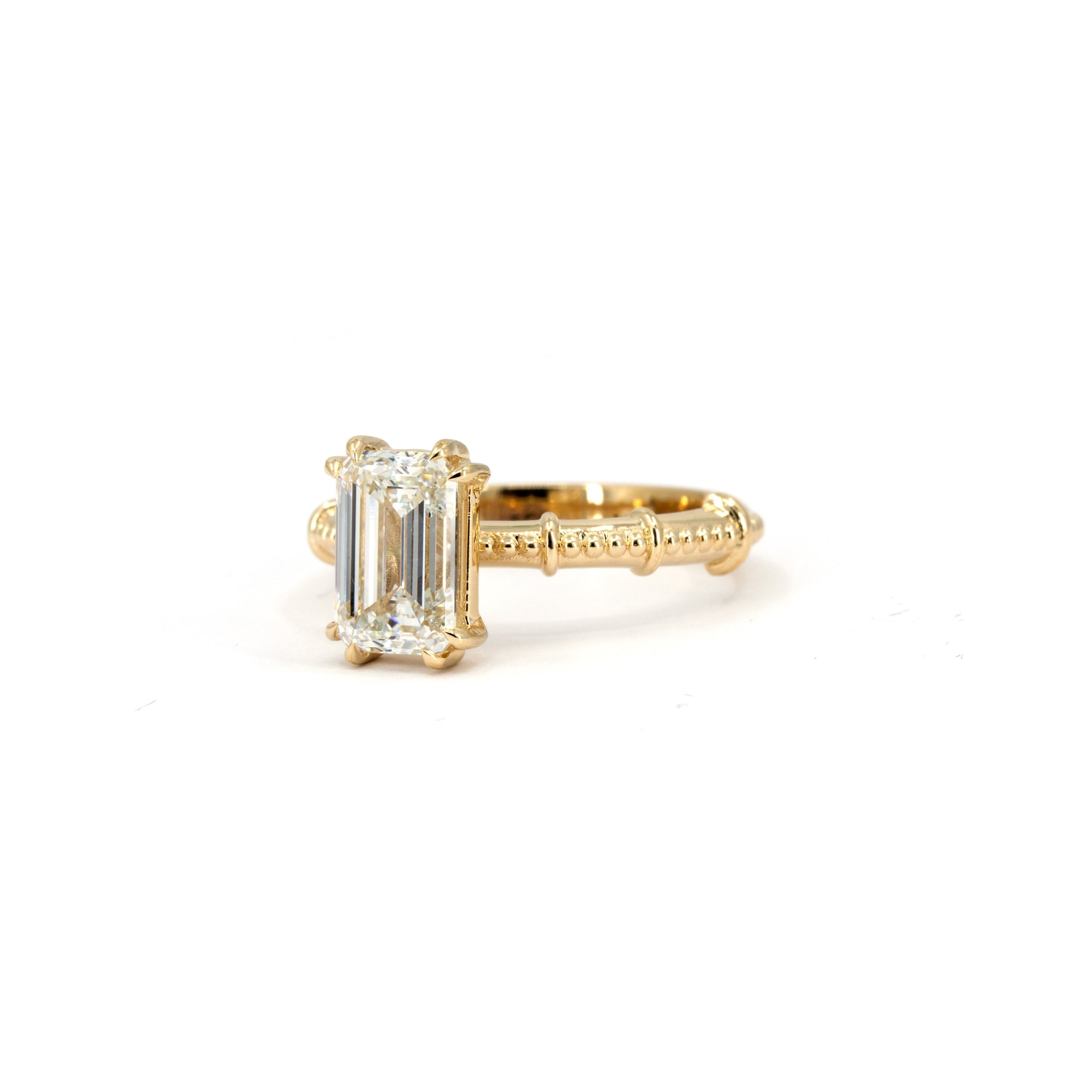 Custom emerald-cut diamond ring in yellow gold, featuring a textured band handcrafted in Montreal, Canada.