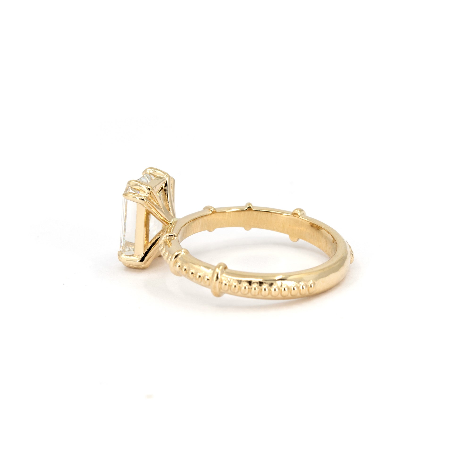 Side view of the Regal Column Ring, showcasing its milgrain texture and the brilliance of the emerald-cut diamond.