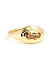 Contemporary yellow gold ring with smooth contours and a central oval champagne sapphire, crafted by Canadian designer Bena Jewelry.