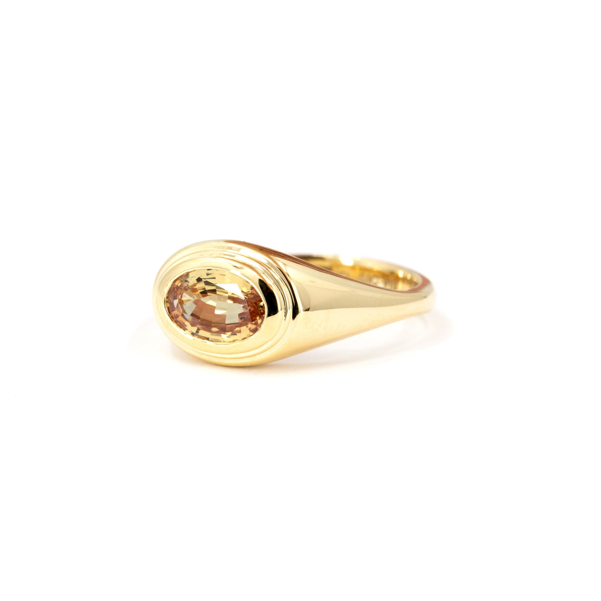 Side view of a fine yellow gold ring with a bezel-set oval champagne sapphire, handmade in Montreal by Bena Jewelry.