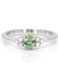 Desir Demantoid Garnet Ring in white gold featuring an oval green garnet and side diamonds by Bena Jewelry photographed on a white background custom-made in Montreal.