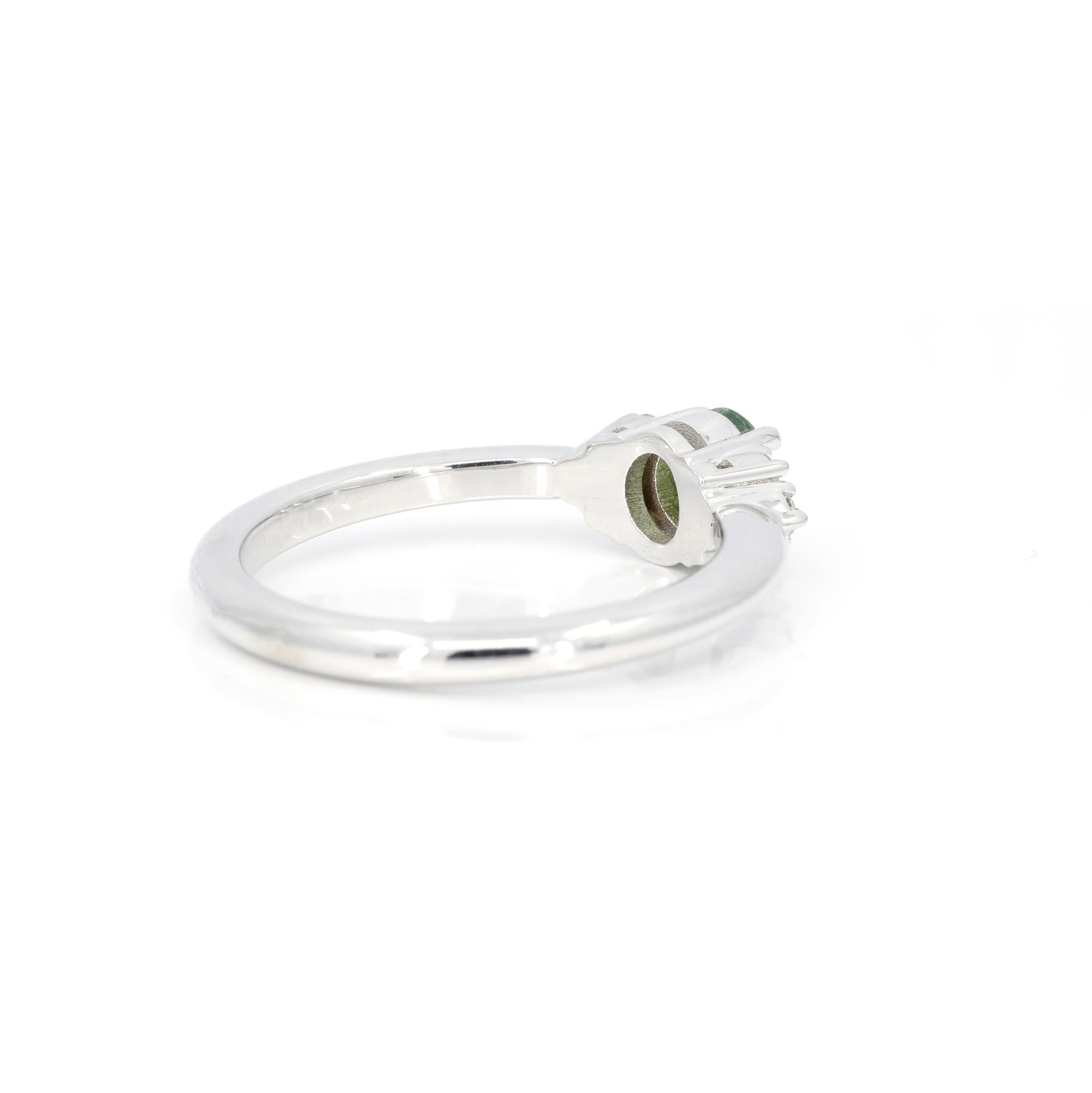 Back view of a white gold engagement ring featuring an oval green garnet and diamonds crafted by Bena Jewelry photographed on a white background.