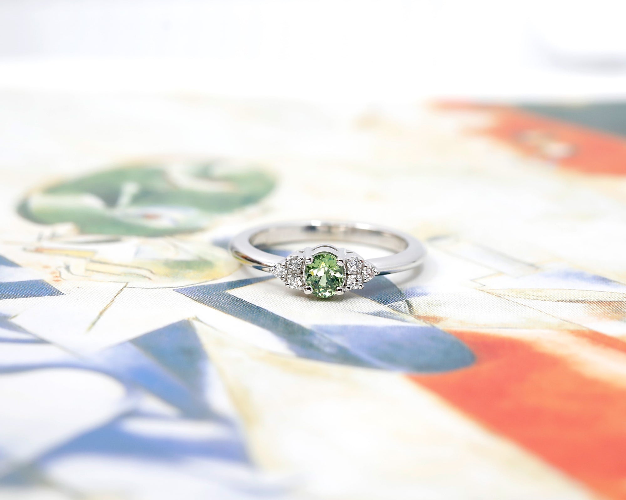 Oval green garnet and diamond ring in white gold by Bena Jewelry displayed on a black matte background modern and unique wedding ring custom-made in Canada