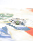 Oval green garnet and diamond ring in white gold by Bena Jewelry displayed on a black matte background modern and unique wedding ring custom-made in Canada