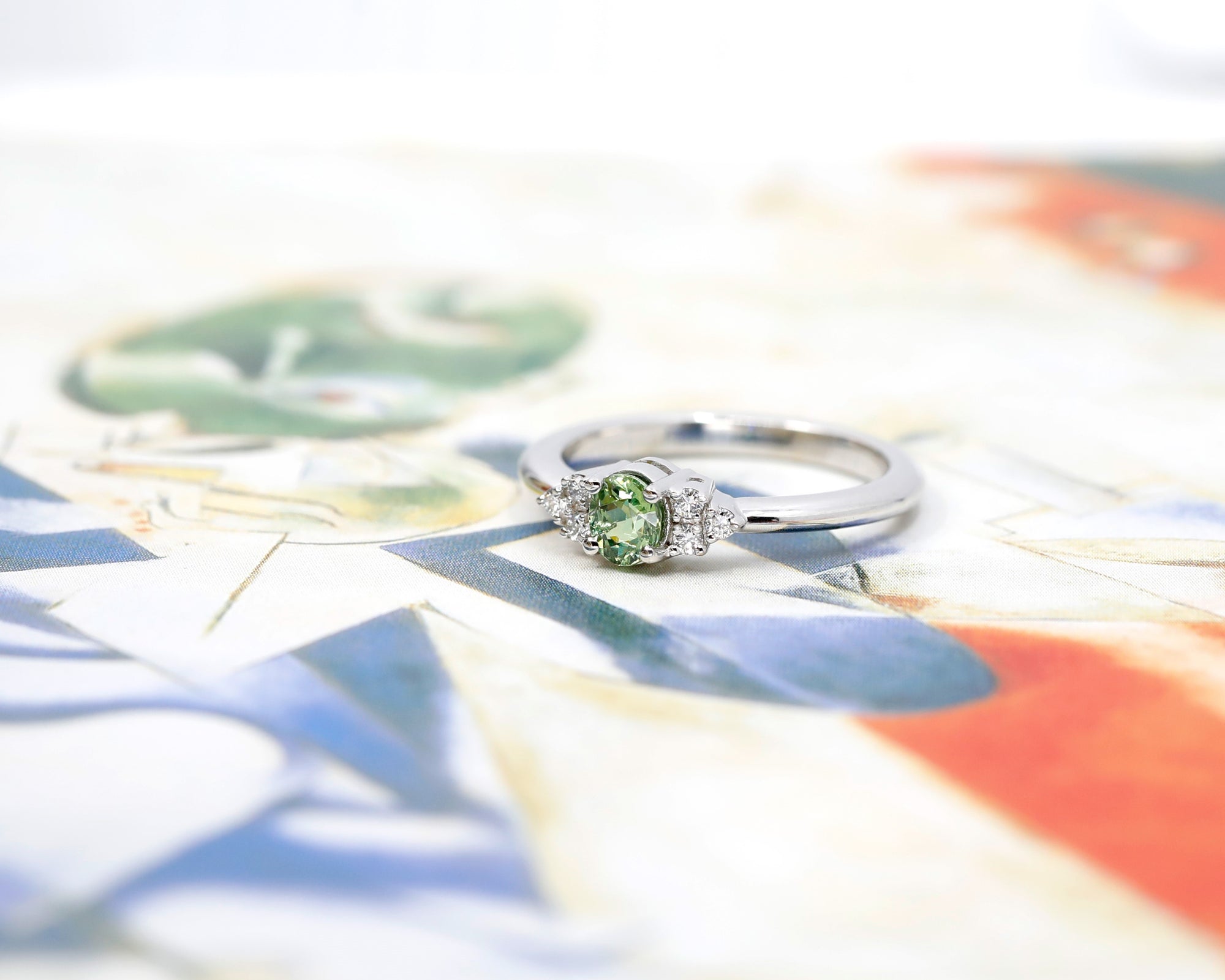 White gold Desir Demantoid Garnet Ring with diamonds by Bena Jewelry photographed on a dark background elegant custom bridal ring made in Montreal