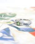 White gold Desir Demantoid Garnet Ring with diamonds by Bena Jewelry photographed on a dark background elegant custom bridal ring made in Montreal