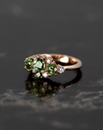 Vibrant green sapphire and demantoid garnet ring in rose gold, displayed on a dark backdrop. Designed by Bena Jewelry in Montreal.