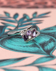 Close-up of Bena Jewelry's Kink Avalanche white gold ring, highlighting the vivid purple and pink sapphires in various cuts and sparkling diamonds, set against a colorful backdrop.