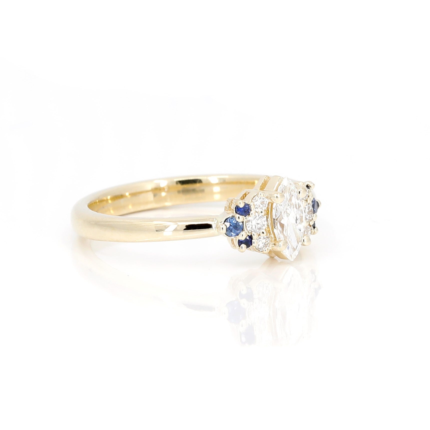 Marquise Diamond and Sapphire Ring in yellow gold by Bena Jewelry, featuring a unique design with diamond accents and vivid sapphires, photographed on a clean white background.