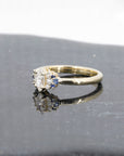 Elegant marquise diamond and sapphire ring in yellow gold by Bena Jewelry, photographed on a dark glossy background, fine bridal jewelry handmade in Montreal.
