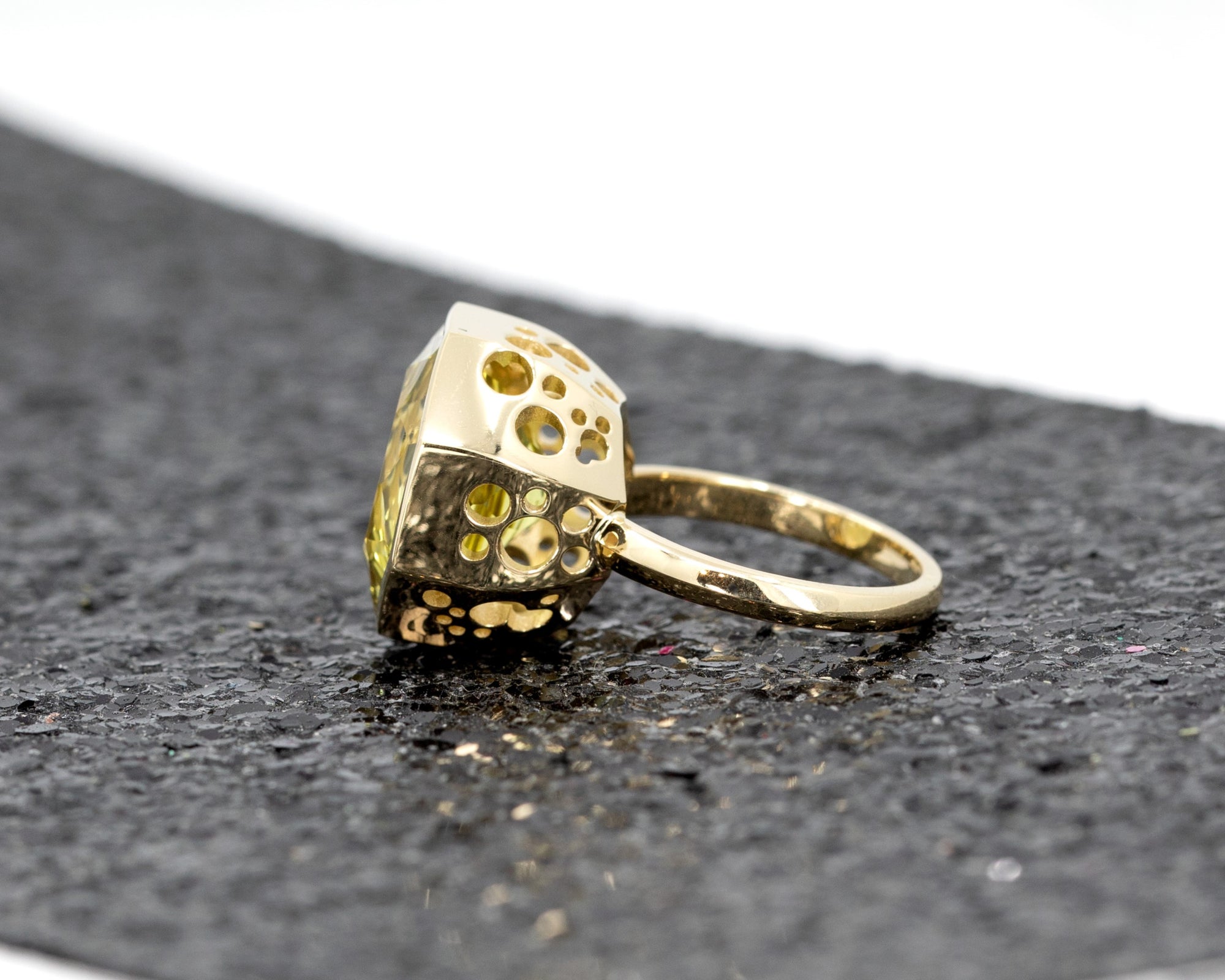 Fancy Edgy cocktail ring featuring a bezel-set yellow gemstone, highlighted by a dramatic dark glitter background.