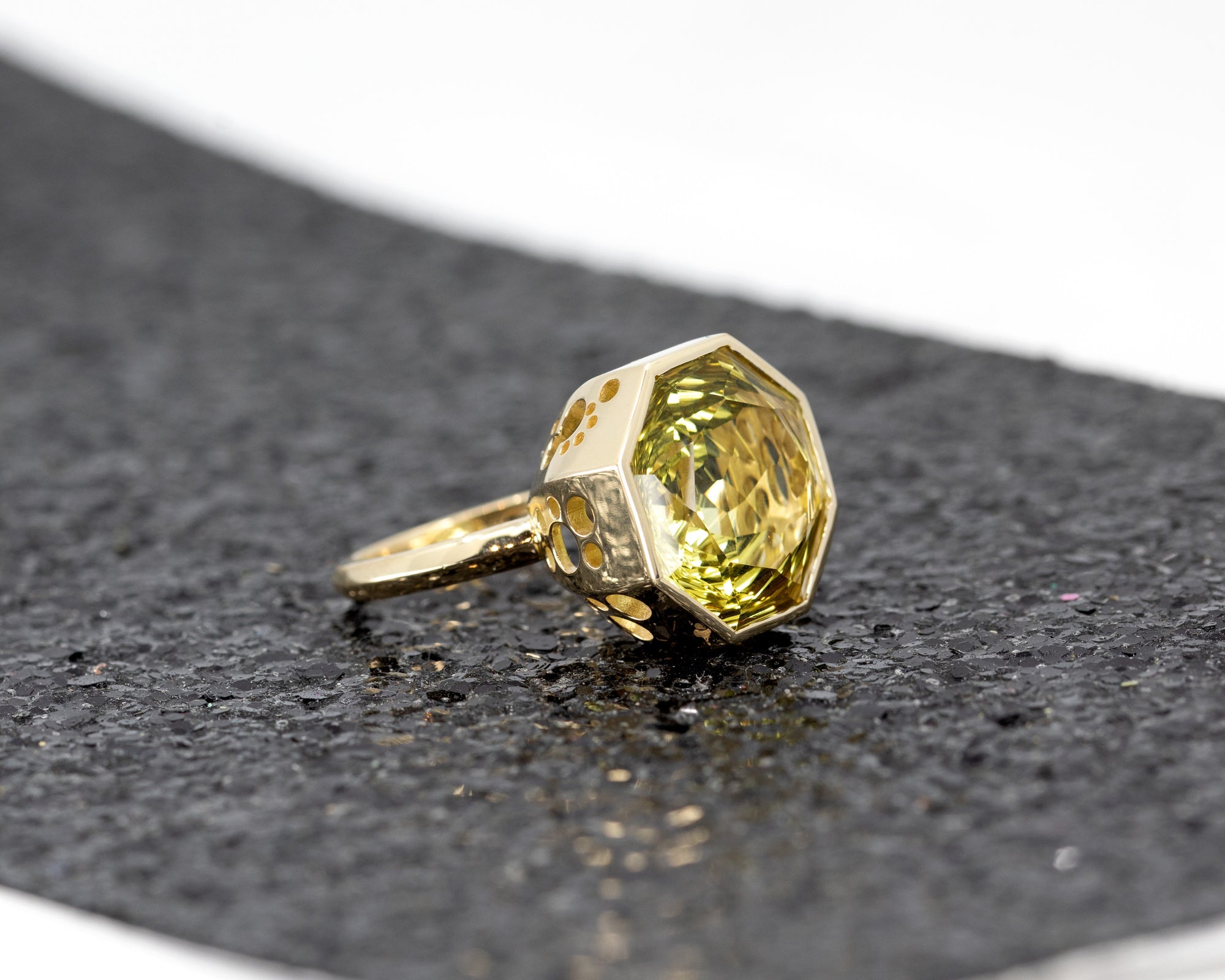 Unique yellow quartz statement ring by Bena Jewelry, glowing against a luxurious black glittery surface.