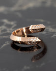 The edgy Loop Ring in rose gold and diamonds, by Bena Jewelry photographed on a deep charcoal surface to accentuate its bold, modern design. Handcrafted in Quebec.