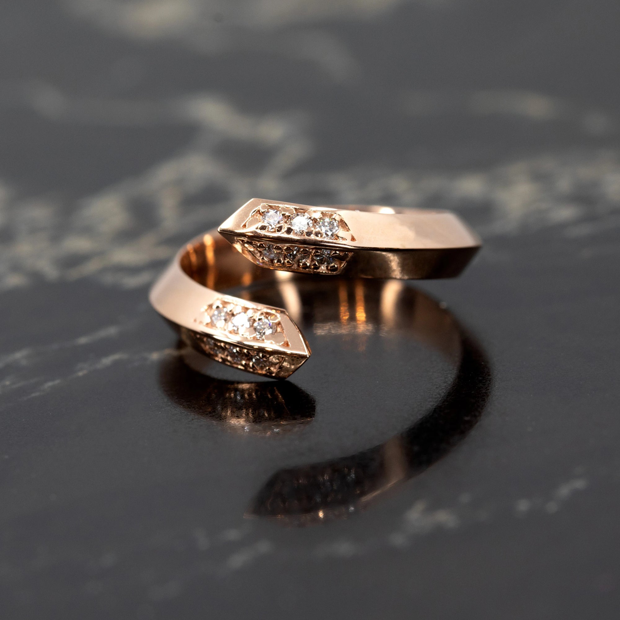 Close-up of the Loop Ring in rose gold, featuring diamond pave and a robust design on a sleek dark background. Made in Montreal by Bena Jewelry.