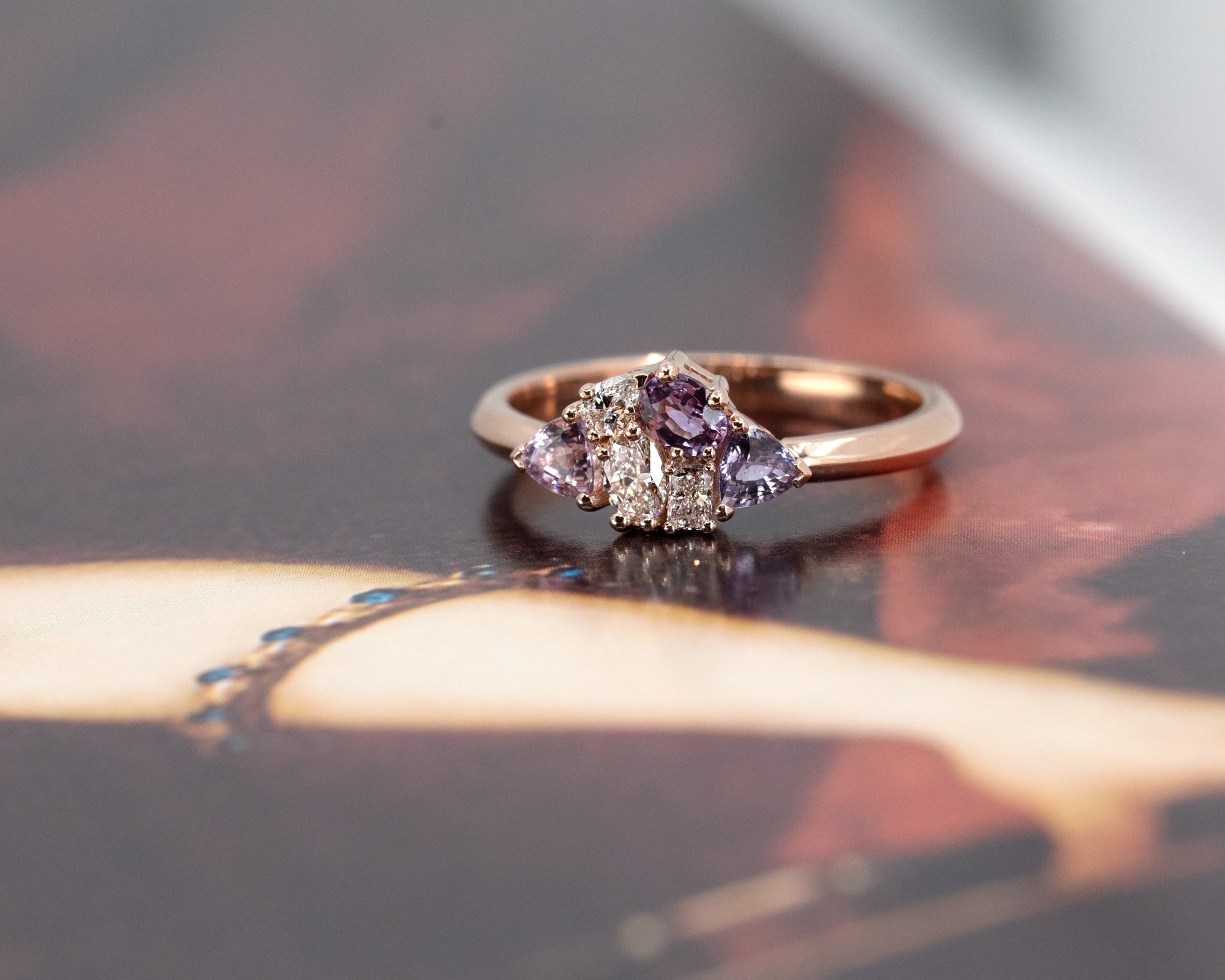 Close-up of the Avalanche ring’s vibrant pink and purple sapphires with sparkling diamonds, set in 14 kt rose gold by Bena Jewelry.