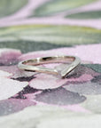 Minimalist open band ring in white gold, photographed on a warm-toned background. The ring’s sleek, curved design and high polish create a refined, modern look.