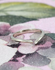 Artistic shot of the Sleek Gap Ring in 14k white gold. The open-ended structure and contemporary silhouette stand out against a bold, contrasting background.
