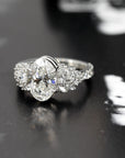 side view of oval shape bridal engagement ring custom made in montreal with central oval shape lab grown diamnonds and marquise pear shape side natural gems on dark background