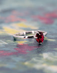 Oval ruby solitaire ring in white gold displayed on a warm-toned background, designed by Bena Jewelry in Montreal.