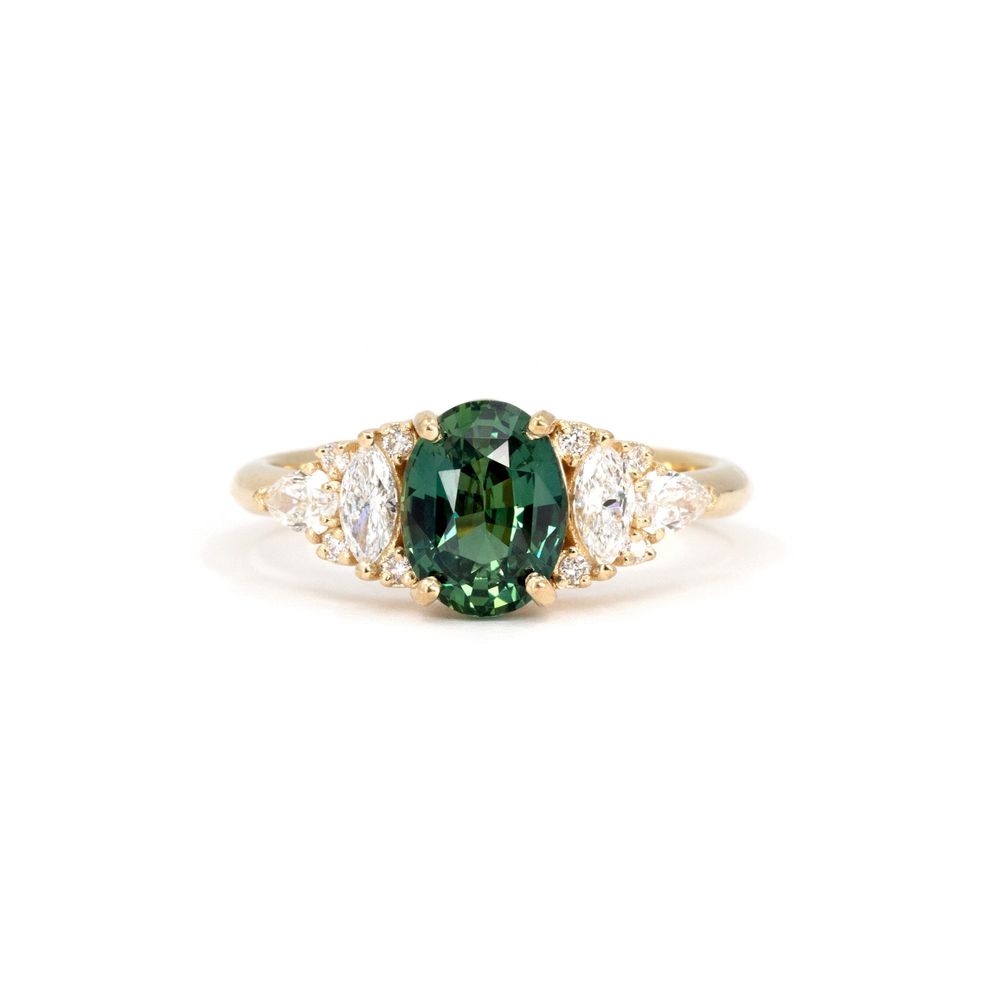 Teal Sapphire Oval Diamond Ring on white background – A bold engagement ring featuring an oval teal sapphire with green hues, accented by marquise and round diamonds in yellow gold. Handmade by Bena Jewelry in Montreal.