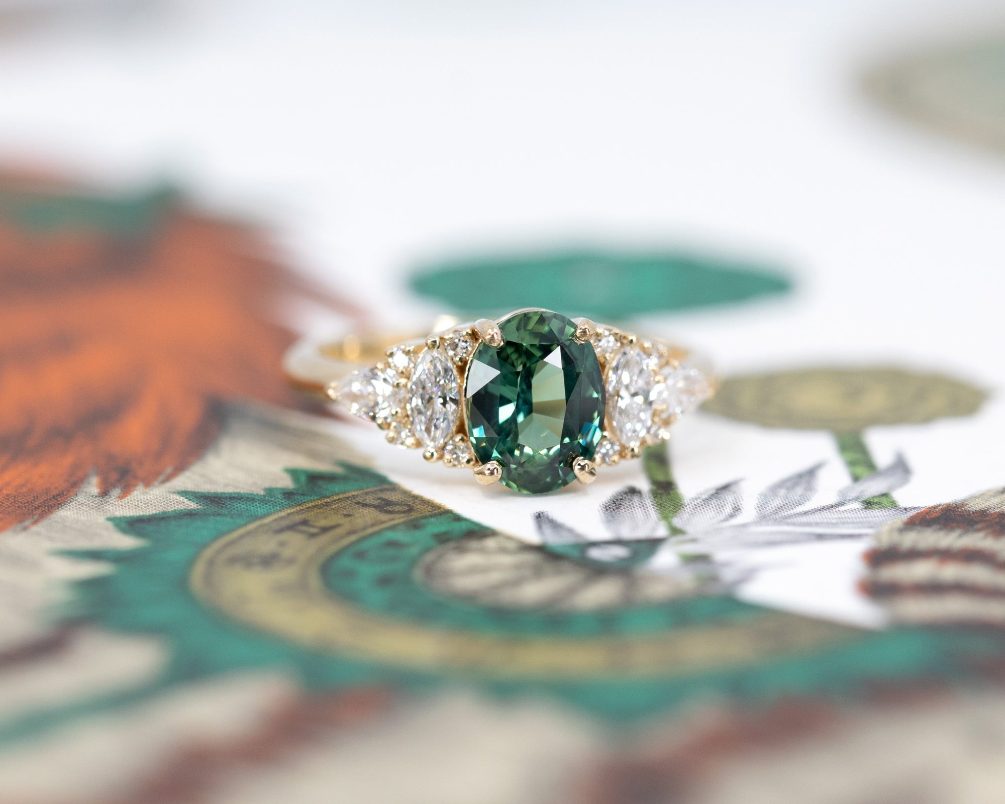 Side view of sapphire and diamond ring – The oval sapphire’s rich blue-green tones contrast beautifully with the warm yellow gold setting.