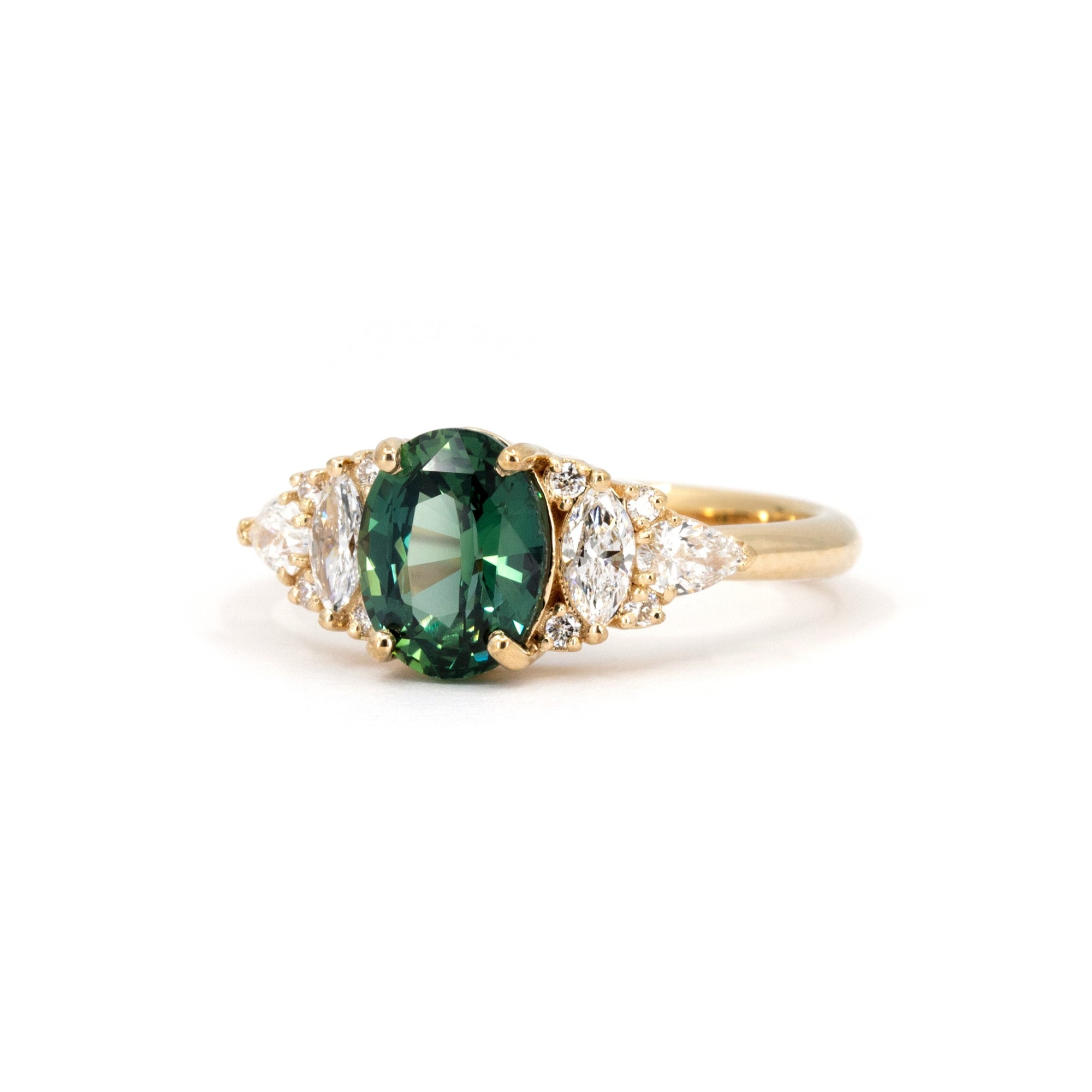 Teal Sapphire Ring on white background – The deep greenish-blue sapphire gemstone glows beautifully against a warm, neutral background.