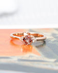 Elegant engagement ring with a peach spinel and diamond accents, displayed on a soft-hued background to enhance its warmth and brilliance. Handmade in Montreal.