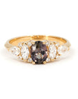 Bena Jewelry engagement ring with oval peacock sapphire and white marquise, pear, and round diamonds on a 14k yellow gold band, photographed on white background.