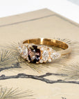 Bold peacock sapphire and diamond ring by Bena Jewelry displayed on a deep-toned background, highlighting the rich hues of the center stone and 14k gold setting.