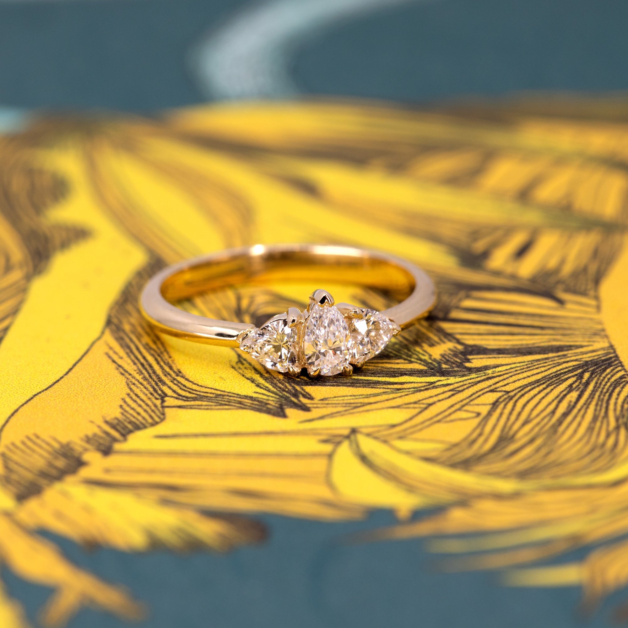 Close-up of the pear-shaped diamond engagement ring, featuring heart-cut side diamonds.