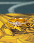 The Heart & Pear Trinity Diamond Ring, a timeless bridal ring displayed against a colored backdrop.