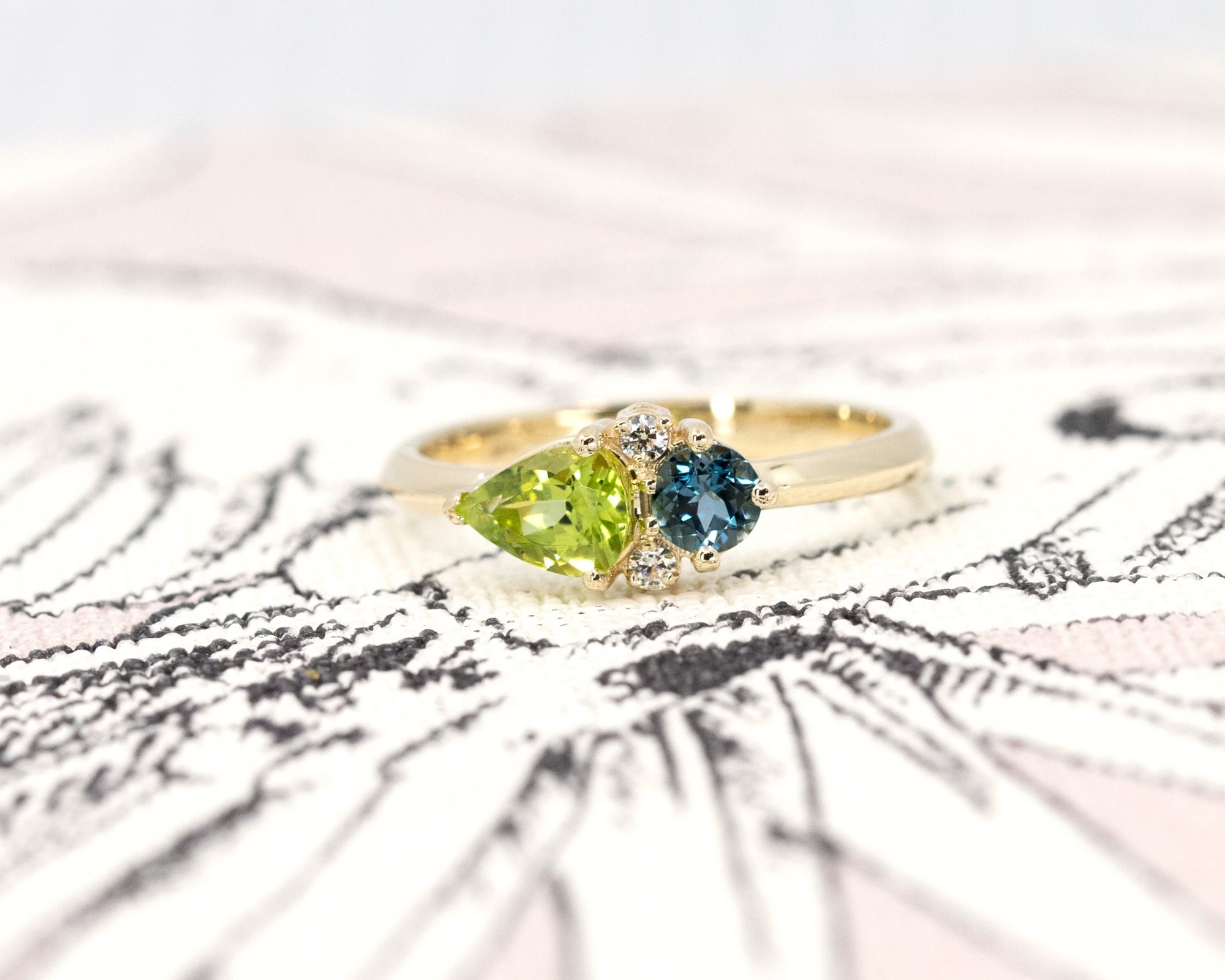 Close-up of the ring worn, showing the interplay of green and blue gemstones – A unique engagement ring crafted by Bena Jewelry in Montreal.