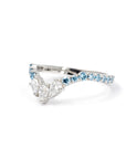 Platinum ring with three pear-cut white diamonds and a row of round blue diamonds, designed by Bena Jewelry in Montreal.