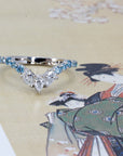 Lifestyle image of the Blue Mirage platinum ring with blue and white diamonds, glowing softly against a colored surface.