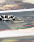 Platinum wedding band with diamonds and a modern pinch design, shown on a soft-colored background. Made in Montreal by Bena Jewelry.