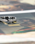 Front view of a designer bridal platinum band with a pinch detail and diamonds, displayed on a vibrant background. Custom-made by Bena Jewelry in Montreal.