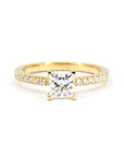 Close-up of a princess-cut diamond engagement ring in yellow gold with pavé-set diamonds on a white background, made by Bena Jewelry in Montreal, Canada.