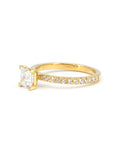 Side view of Bena Jewelry yellow gold ring featuring a central princess-cut diamond and diamond pavé band, photographed on white.