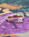 Contemporary engagement ring in 18k yellow gold with diamond pavé, designed by Bena Jewelry, shown against a muted color background.