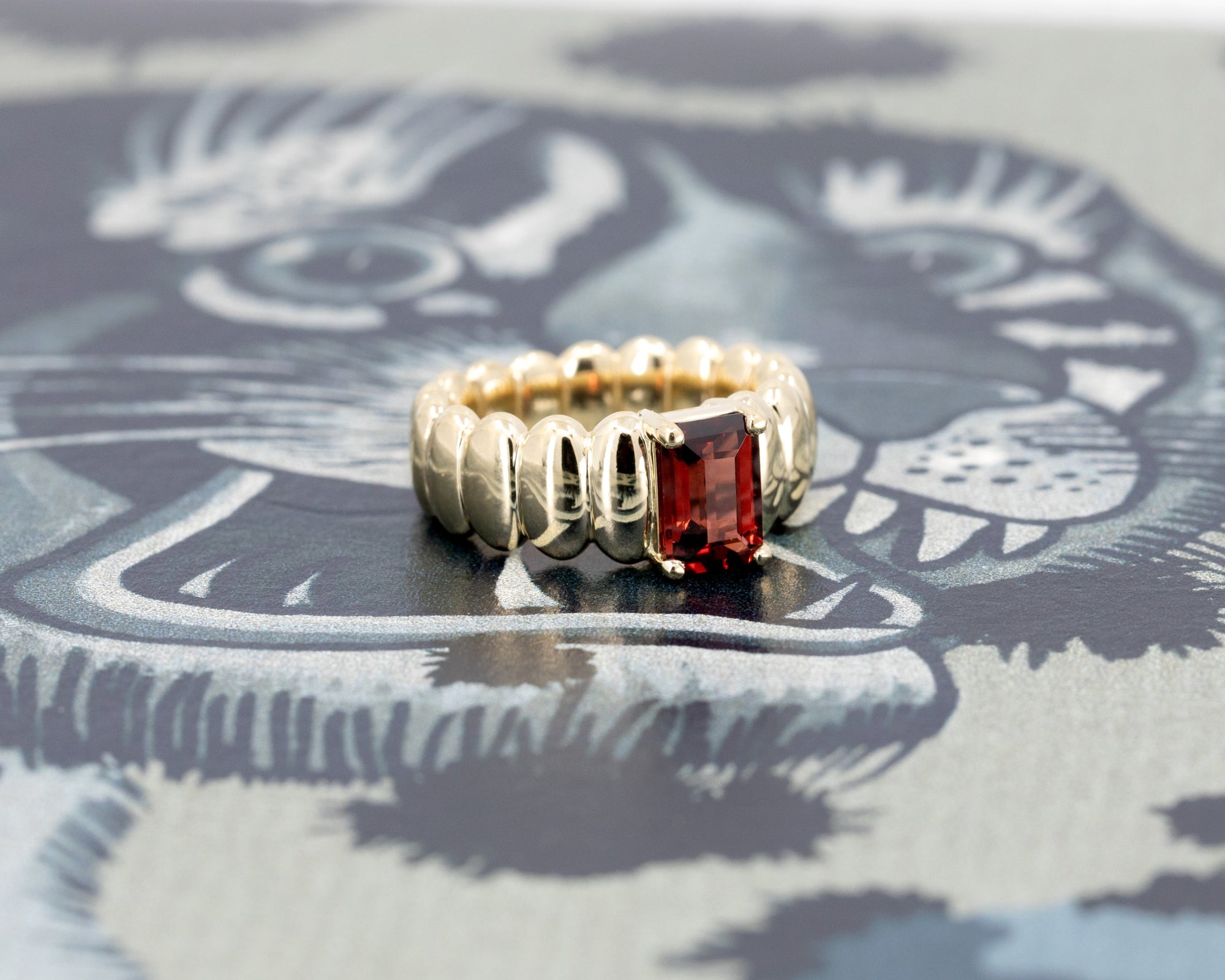 Close-up of the Pyrope Pigalle Ring, focusing on the pyrope garnet’s vibrant color and precise cut, framed by the sleek yellow gold setting by Bena Jewelry.
