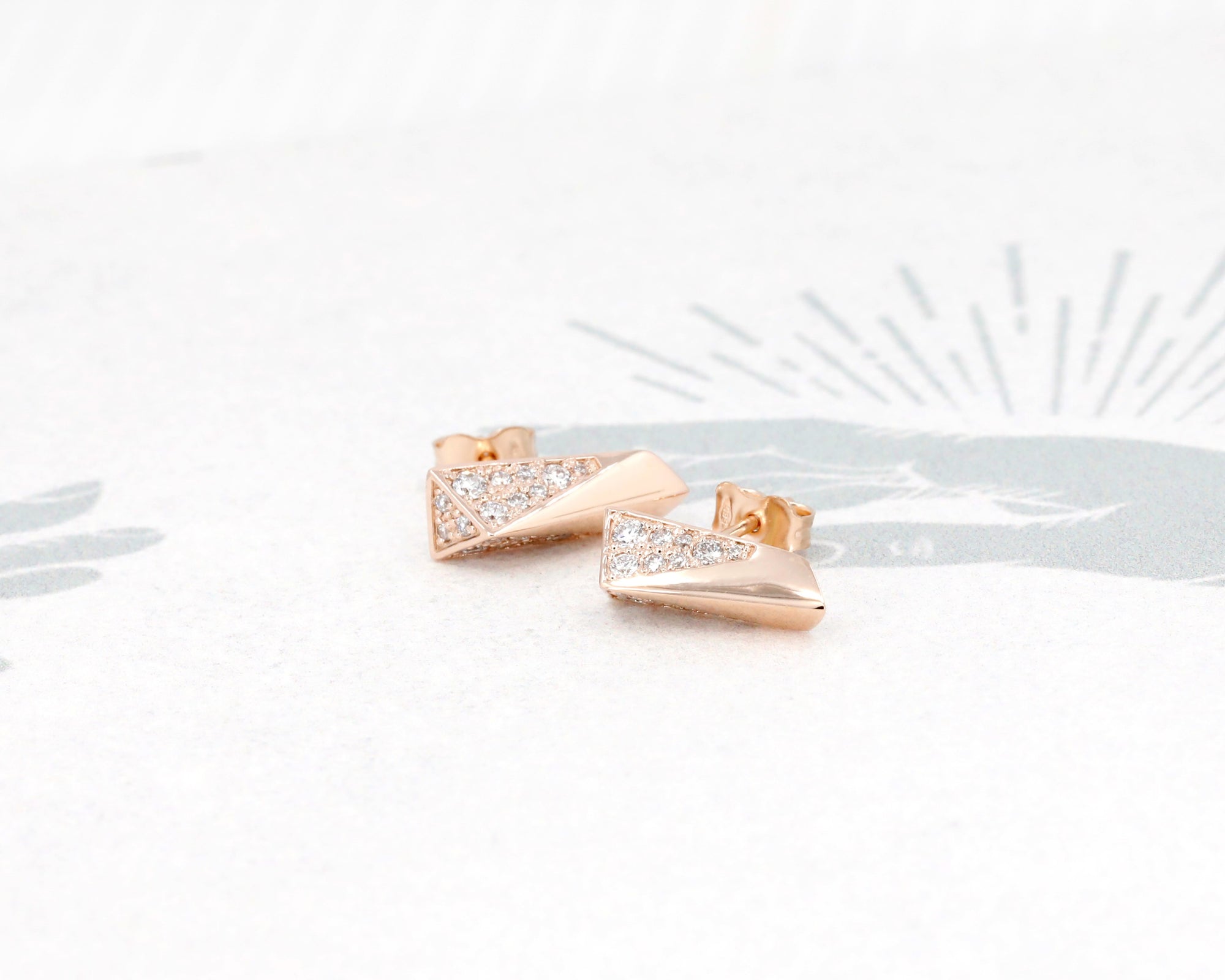 Rose Gold Pike Earrings Half Diamond displayed against a dark background, emphasizing the brilliance of the diamond pavé.