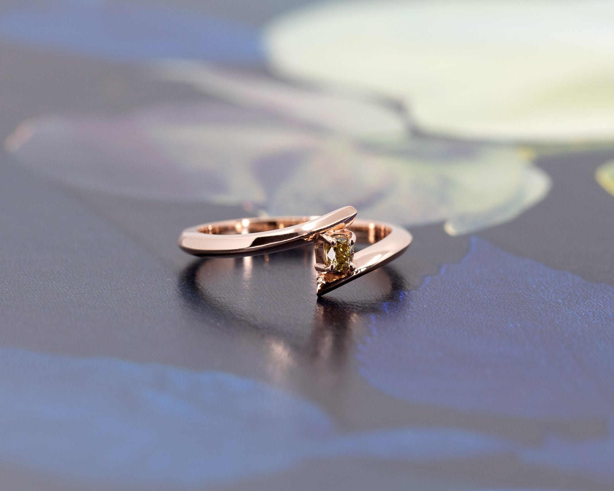 Minimalist engagement ring featuring a natural yellow diamond in rose gold by Bena Jewelry, displayed on a black matte background. Custom-made in Canada.